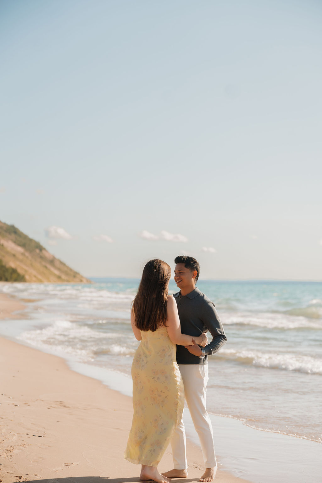 Couple posing along the shoreline at Empire Beach after their surprise Sleeping Bear Dunes proposal