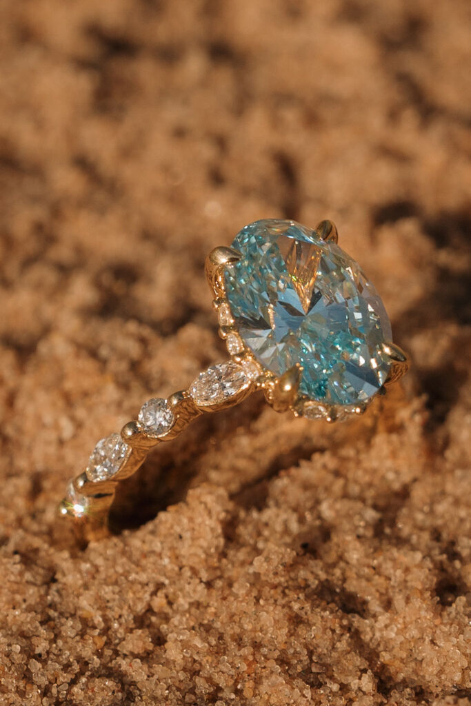 Oval engagement ring placed in the sand from a Sleeping Bear Dunes proposal in Northern Michigan.