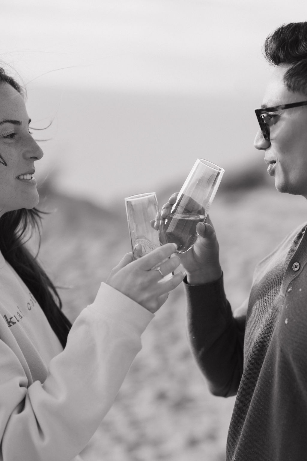 Black and white photo of a couple toasting champagne after their Northern Michigan proposal.
