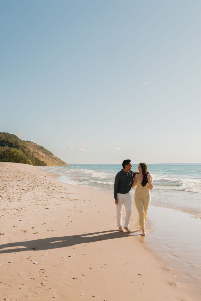 Couple smiling at each other and walking along the shoreline at Empire Beach.