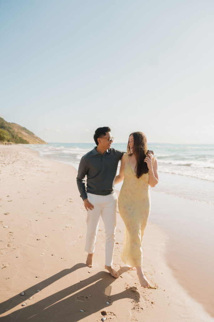 Couple smiling at each other and walking along the shoreline at Empire Beach.