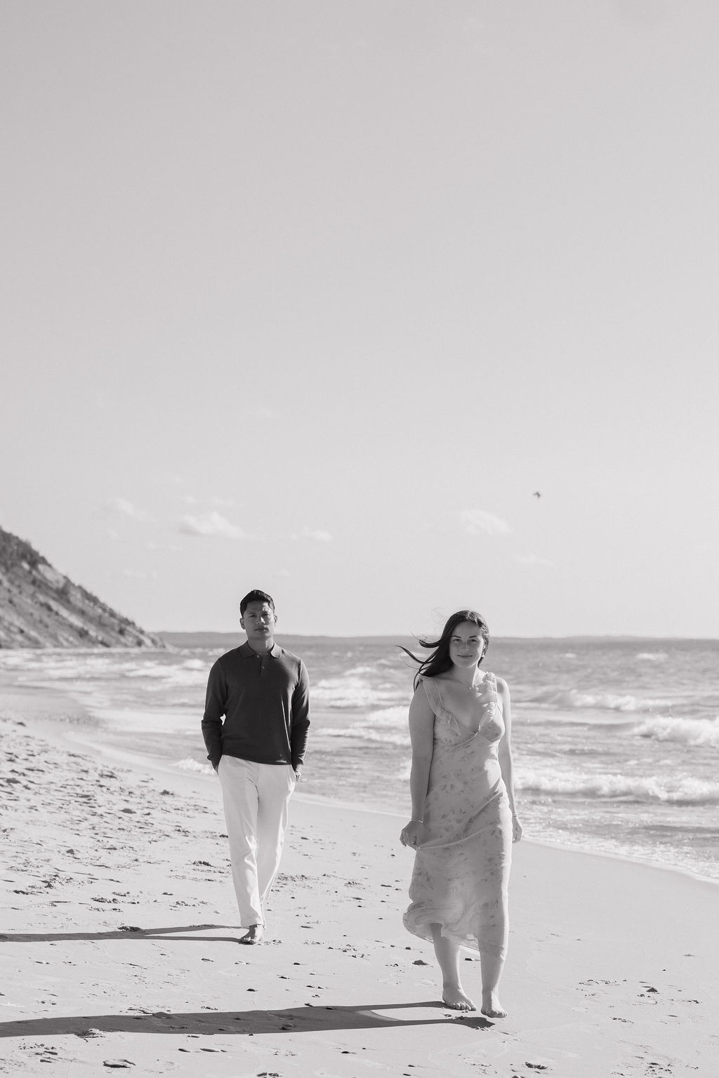 Black and white photo of a couple walking along the shoreline at Empire Beach.