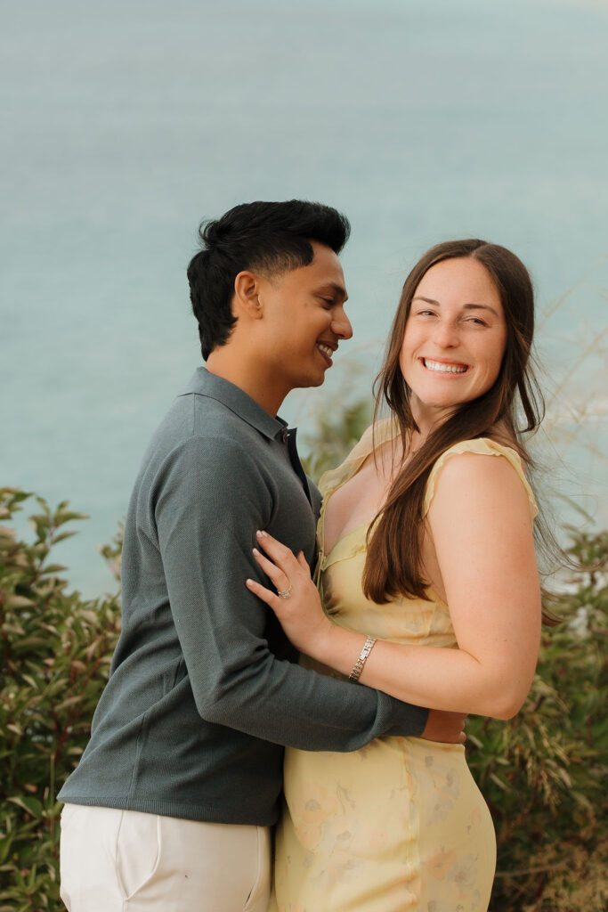 Woman smiling at the camera as her fiancé holds her waste.