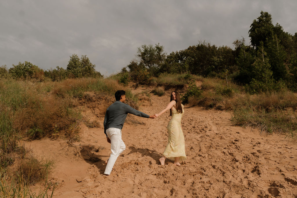 Couple holding hands and walking along the sand dunes at Empire Bluff.