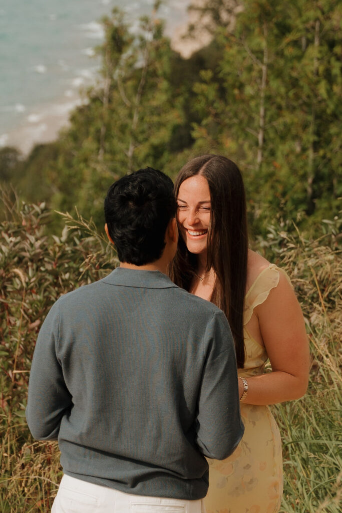 Woman smiling just before her fiancé proposes to her.