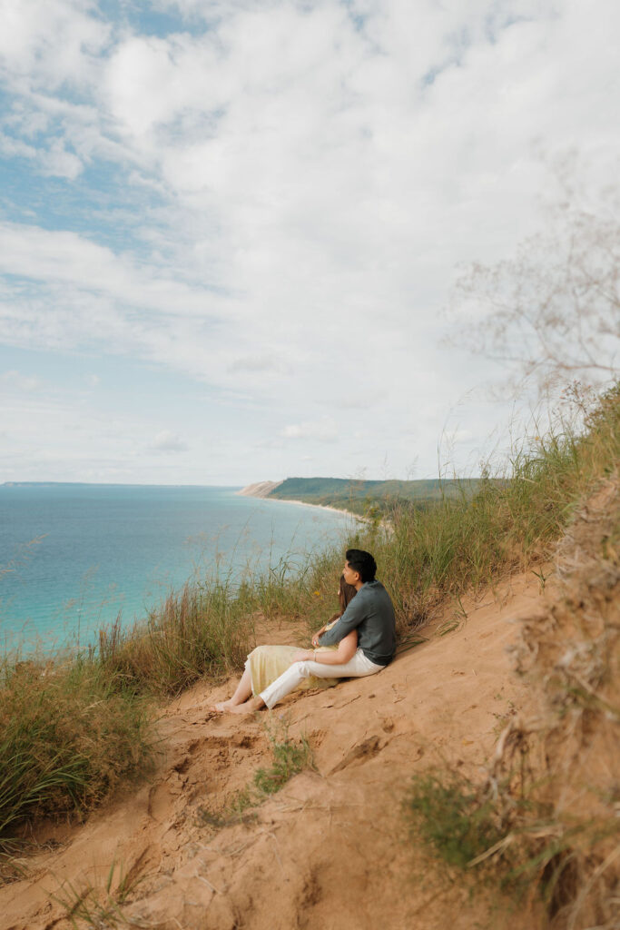 Couple admiring Lake Michigan and laying in the sand of the dunes at Empire Bluff for their Sleeping Bear Dunes proposal.