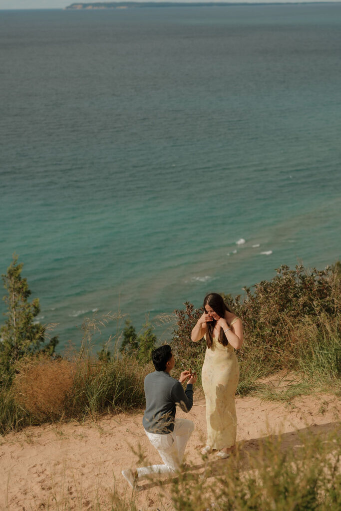Man kneeling on one knee during a surprise Sleeping Bear Dunes proposal at Empire Bluff