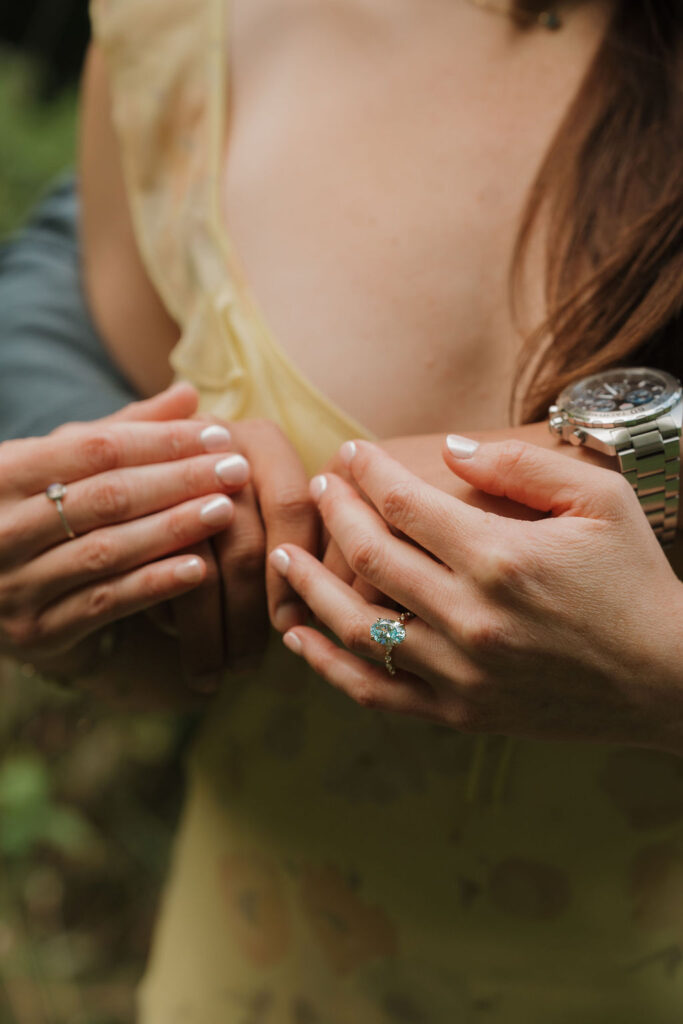 Close up shot of a couple holding hands showing an engagement ring.