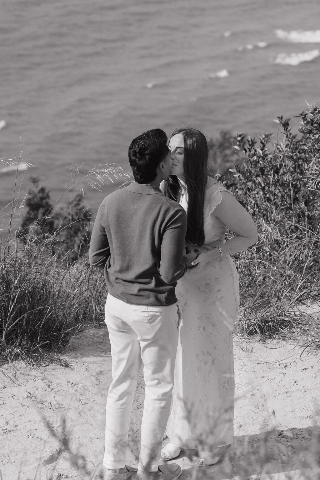 Black and white photo of a couple kissing after their proposal at Empire Bluff.