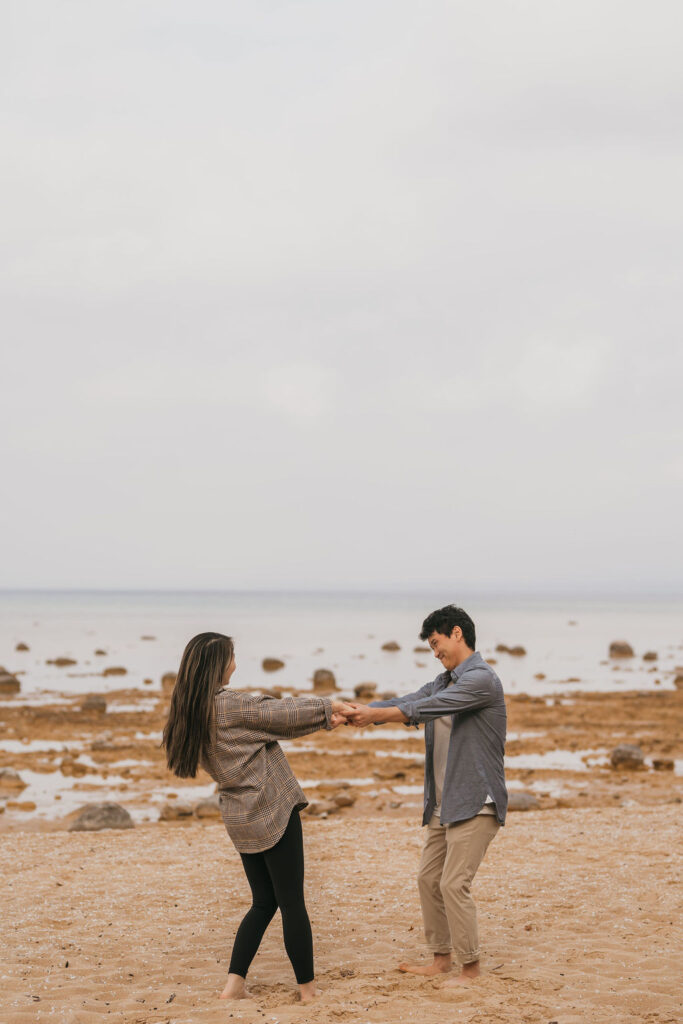 Couple holding hands on the beach during their their Traverse City Michigan proposal photos