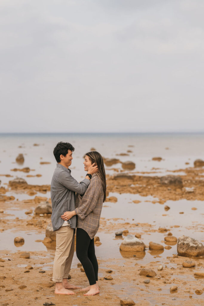 Couple holding each other on the beach during their Northern Michigan proposal.