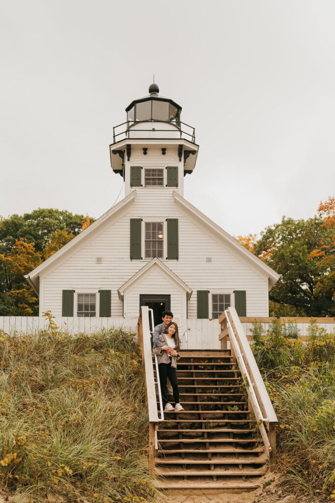 Couple posing on the stairs at Old Mission Lighthouse for their Traverse City Michigan proposal photos.