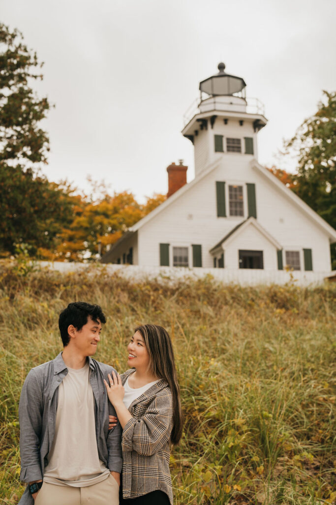 Couple posing side by side in front of Old Mission Lighthouse for their Traverse City Michigan proposal photos.
