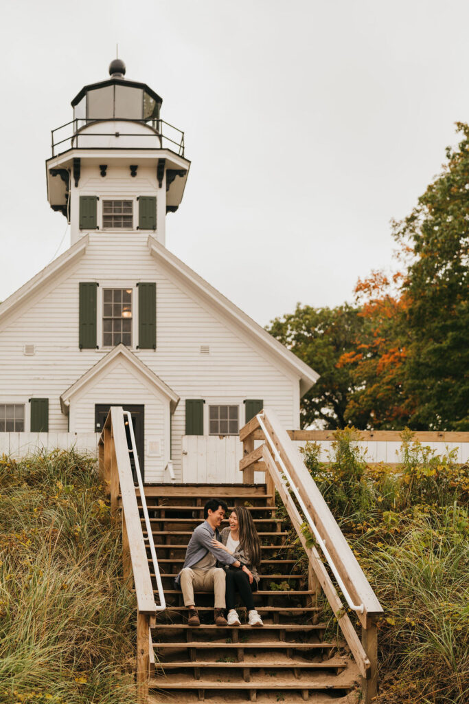 Couple sitting on the stairs at Old Mission Lighthouse for their Traverse City Michigan proposal photos.