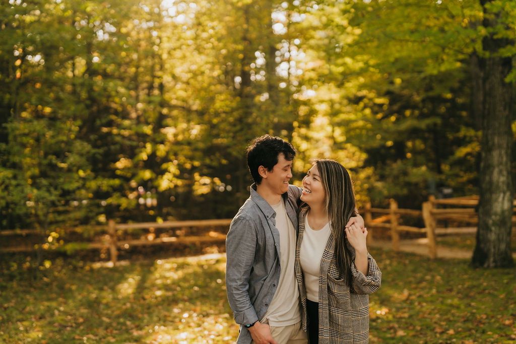 Couple smiling at each other during their fall proposal photoshoot in Northern Michigan.