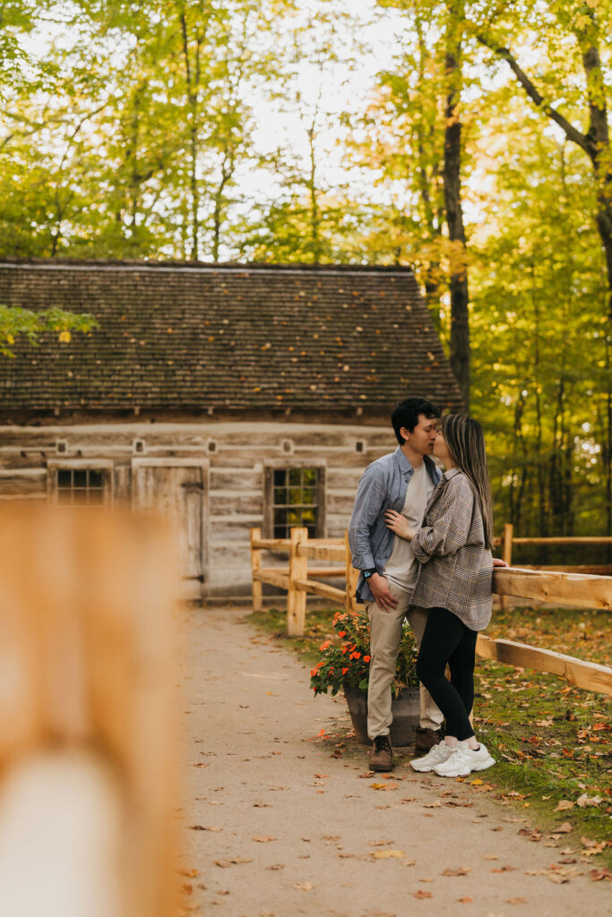 Couple kissing in front of a cabin at Old Mission Lighthouse for their Traverse City Michigan proposal.