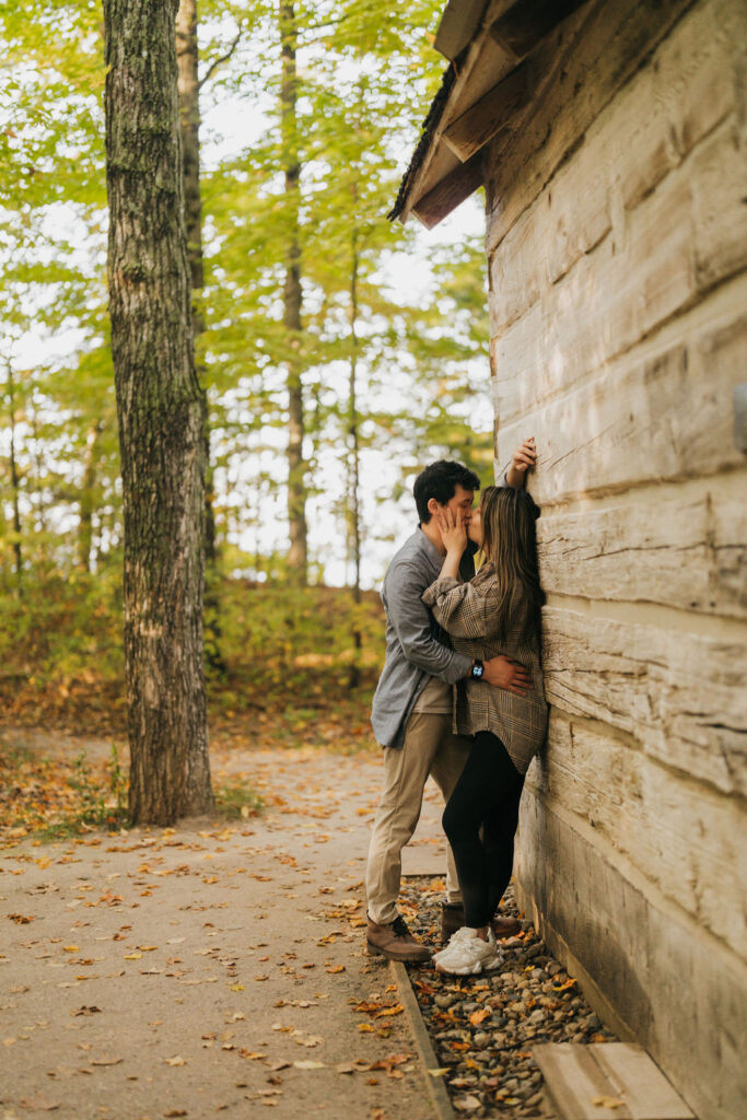 Couple kissing against the cabin at Old Mission Lighthouse for their Traverse City Michigan proposal photos.