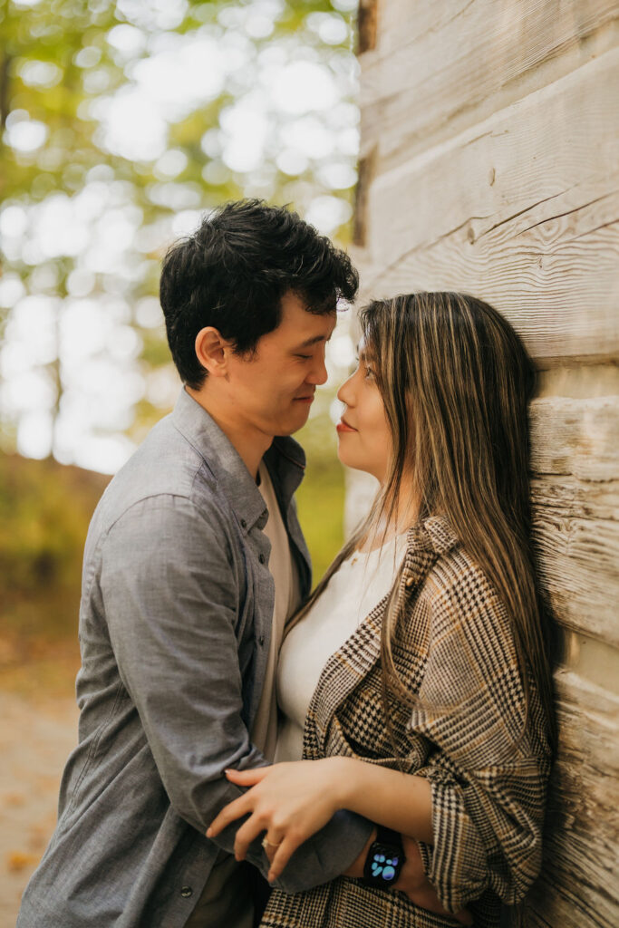 Close up of a couple posing against a cabin in TC Michigan.