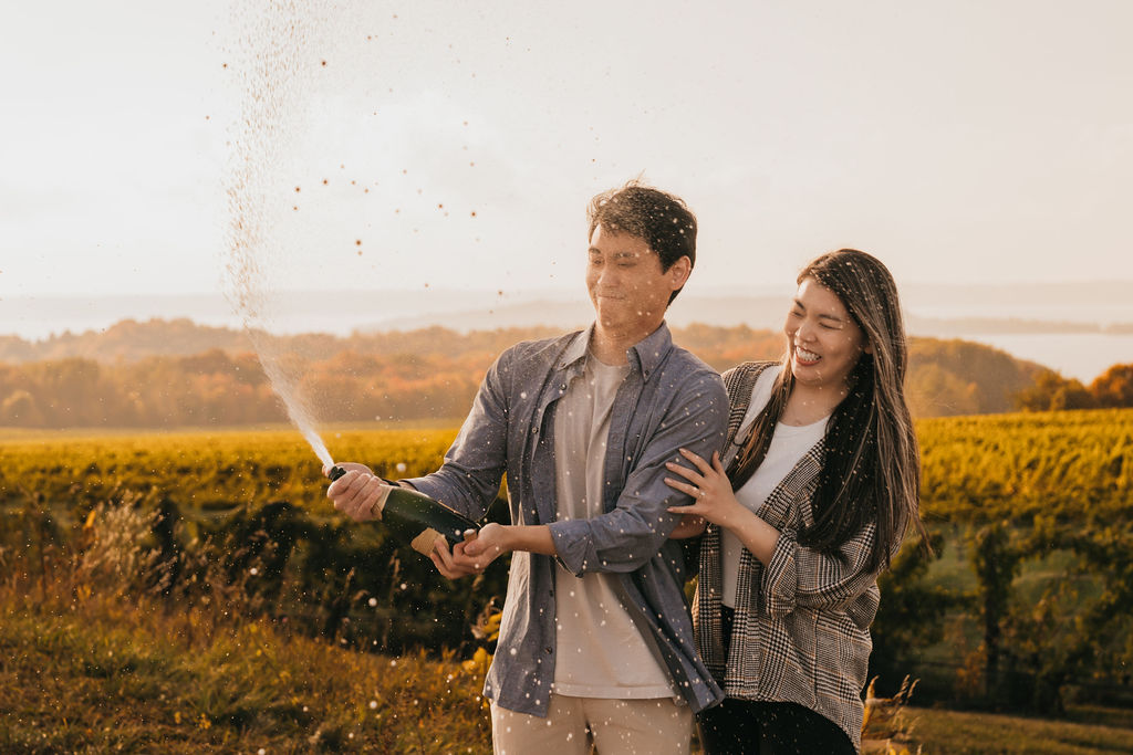 Couple popping champagne during golden hour at The Overlook for their Traverse City Michigan proposal.
