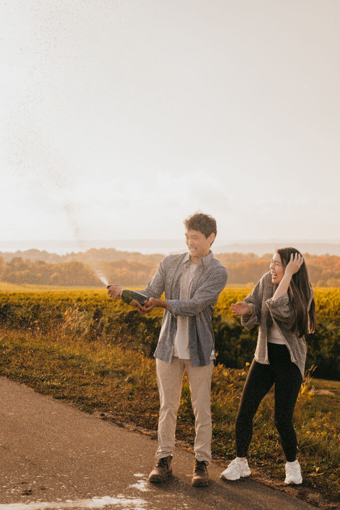 Couple popping champagne during golden hour at The Overlook for their Traverse City Michigan proposal.