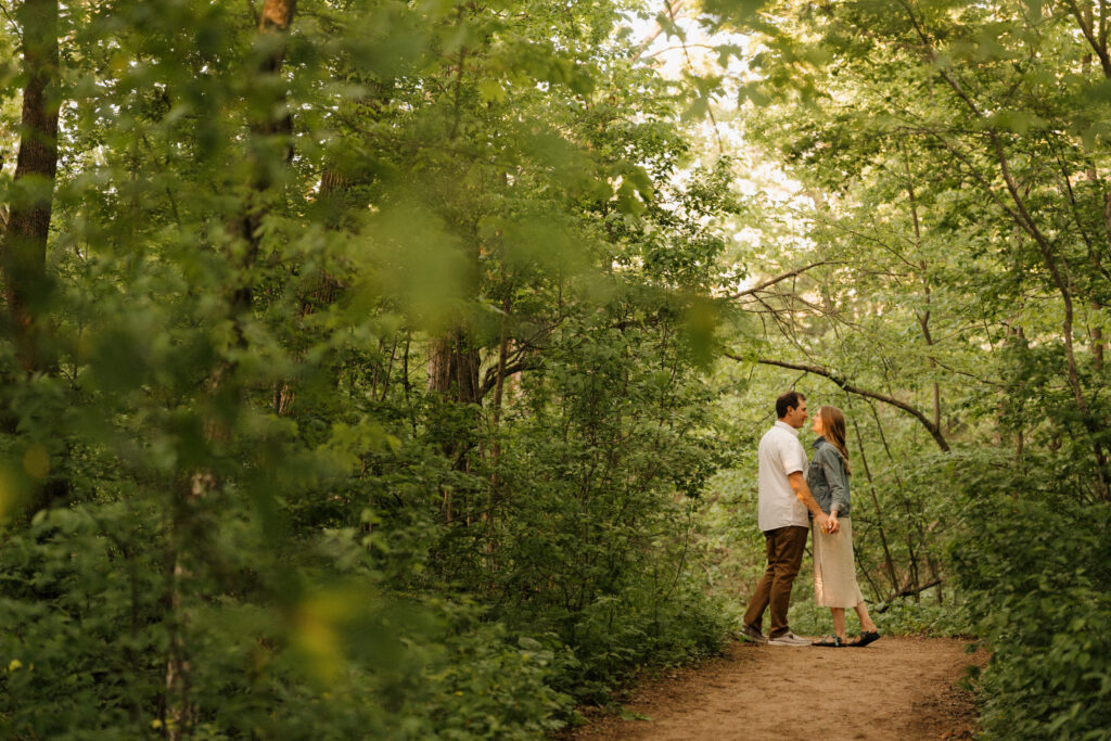 couple kissing in the forest celebrating their recent engagement