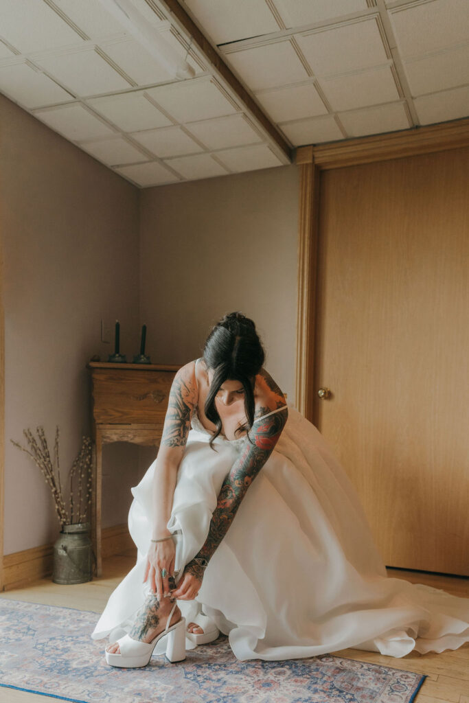 bride putting her wedding shoes on before walking down the aisle of her wedding