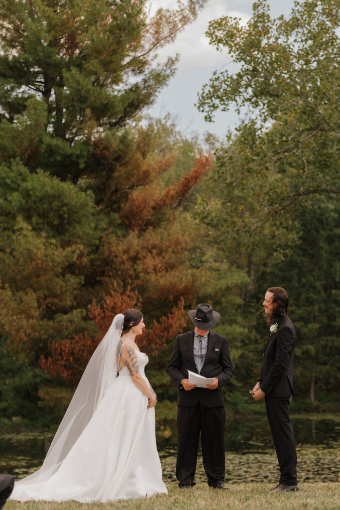 groom and wife during their wedding ceremony in the hills of brooklyn mi