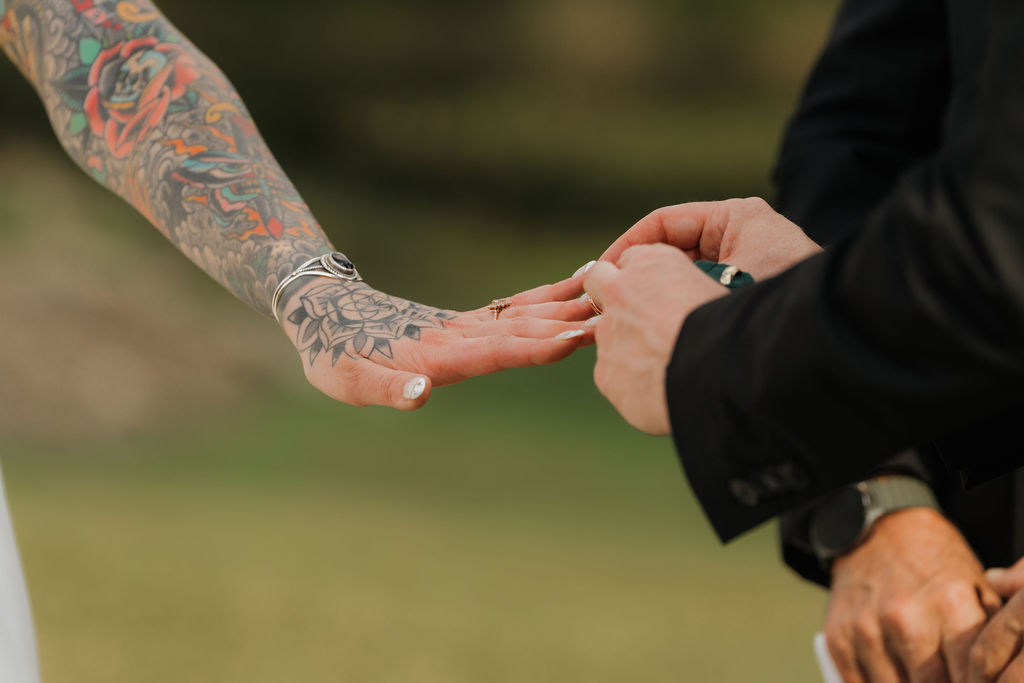 groom placing the wedding ring on his wife's finger during an intimate ceremony