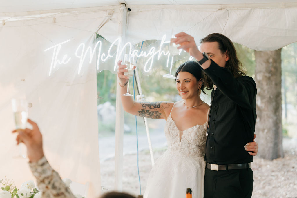 bride and groom standing next to each other, holding up their glasses in a toast at their wedding reception in michigan