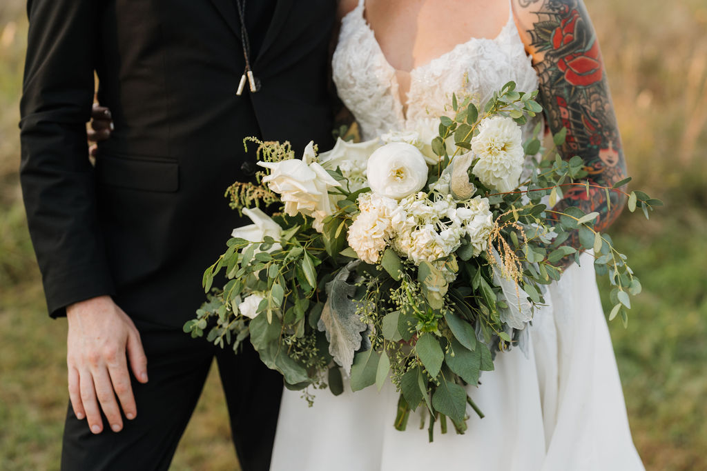 bride holding her wedding bouquet and standing next to her groom during their couple's photos after their ceremony