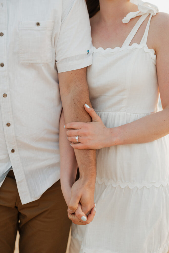 couple holding hands on empire beach in MI during engagement photo session