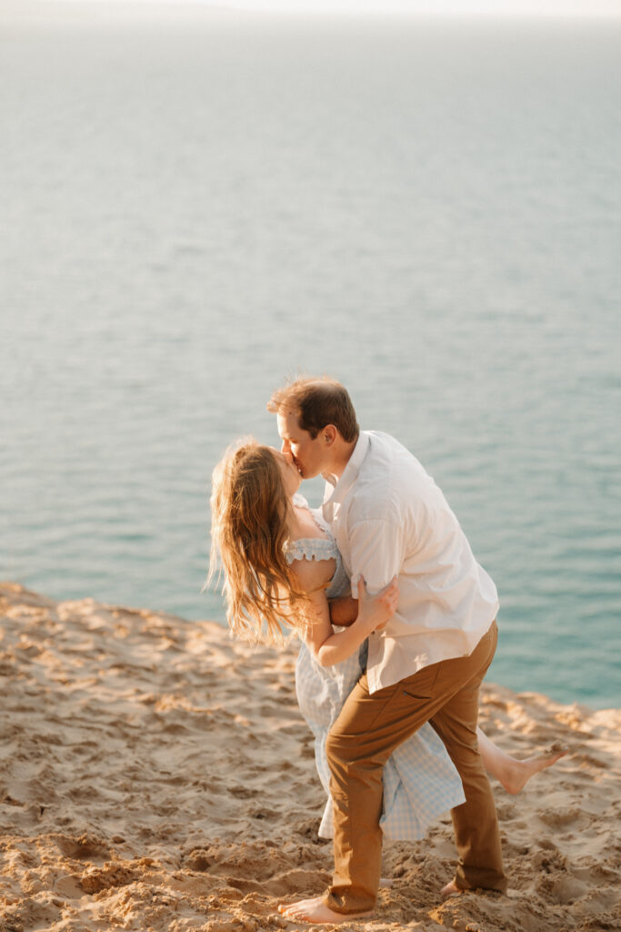 groom dipping bride into a romantic kiss on the sleeping bear dunes