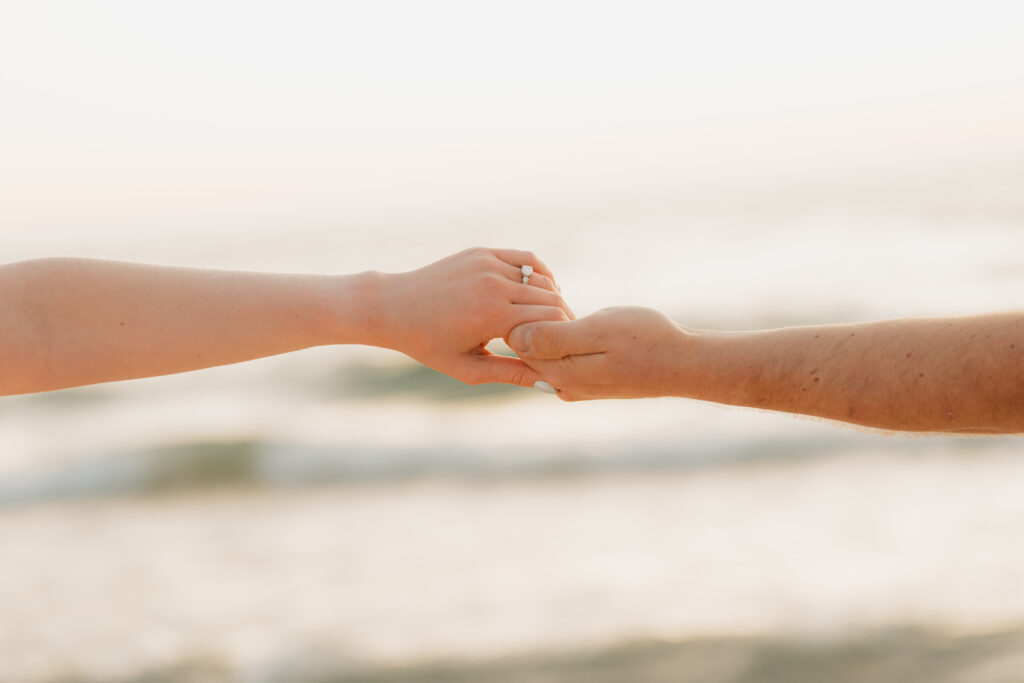 engaged couple holding hands at empire beach at sleeping bear dunes