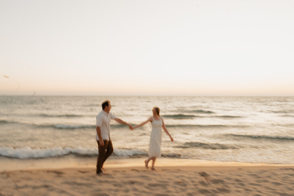 engaged couple walking across empire beach and holding hands